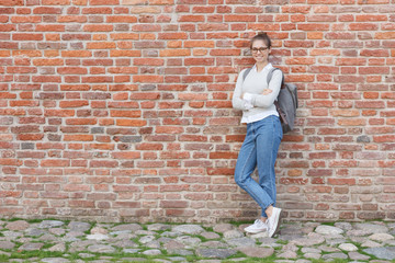 Full-height portrait of young European woman wearing eyeglasses and casual clothes, leaning to red...
