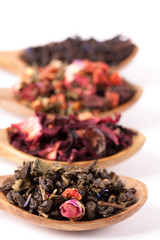 Fototapeta na wymiar Dry tea in wooden plates, on white background. Leaves of red, green and black tea. Macro photo.