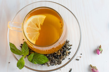 A glass cup of green natural tea with ginger, lemon, mint and honey on wooden rustic background. Healthy drink.