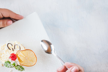 Tasting creamy orange dessert serving on square cut plate in restaurant. Delicious cake decorated by dried citrus, cherry and mint, close up picture