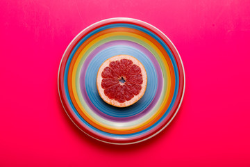 Red grapefruit slice on plate. Flat lay.