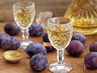 Plum brandy Slivovtz in crystal glasses and plums on wooden background. Traditional Croatian drink.