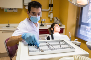 Dentist man making treatment for patient and taking instruments in modern cabinet.