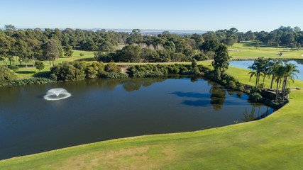 Aerial view of golf course water hazard dam surrounded by tree lined fairways