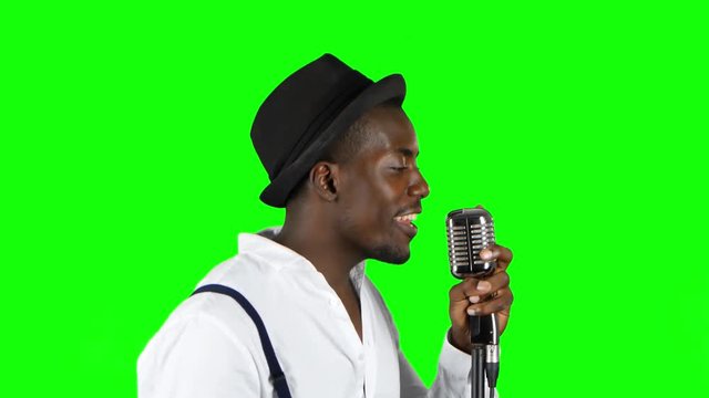 Male african american musician in half of the turnover singing in a recording studio. Green screen. Close up