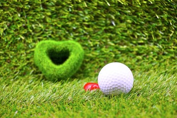 Golf ball with heart shape on green grass