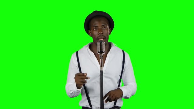 Man singer sings into a microphone and dance. Green screen