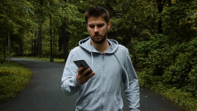 Clumsy sportsman runner dropping new iphone while running or jogging in park. He looks very confused and try to catch selfphone. Slow motion rapidly shot in 250 fps.