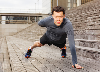 Sportsman doing push-ups on one hand outdoors