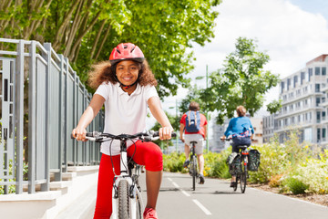 Happy African girl cycling on bicycle path in city