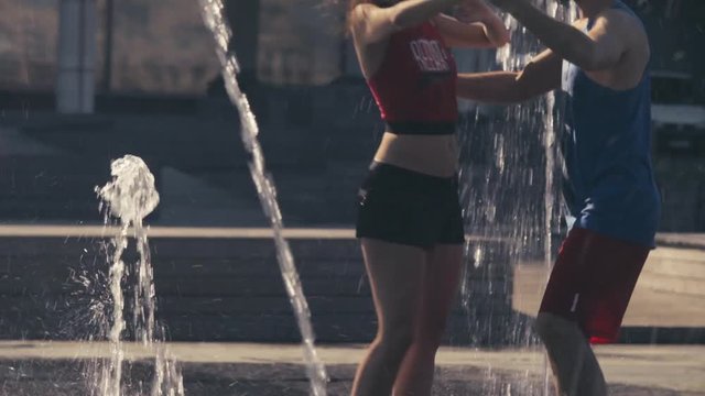 Young happy couple dancing in the fountain