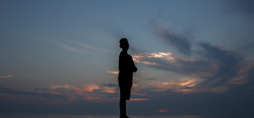 Junge vor einem bewölkten Himmel im Sonnenuntergang