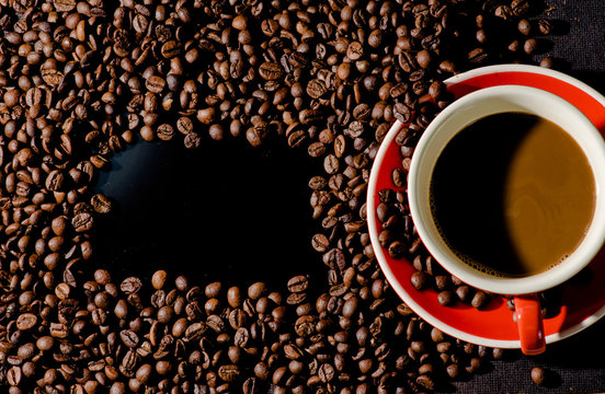 
Hot coffee in red cup and coffee beans are the background.