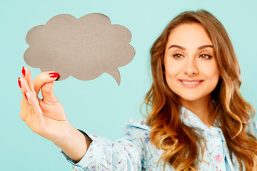 Young woman holding empty thought bubble over blue background