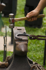 Farrier producing horseshoes in the traditional method on an anvil. Selective focus on the shoe