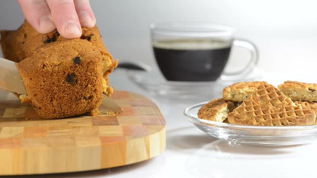 Hands cut cake with raisin on a chopping board a sharp knife