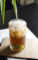 Cocktail cube libre on black table with palm tree on background