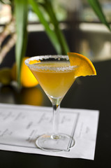Cocktail sidecar on black table with palm tree on background