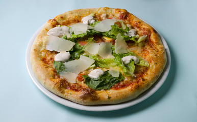 Caesar pizza on a white plate on a blue background