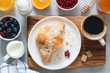 Fresh croissant, jam, cup of coffee, fruits and berries, boiled egg and honey. Continental breakfast table top view