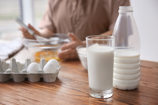 Glass with fresh milk on table and blurred woman on background