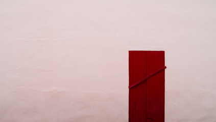 Closed permanently red wood door on pink concrete wall with copy space