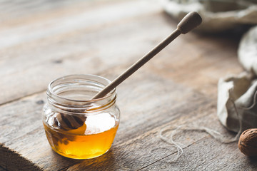 Jar of honey and honey dipper on wooden table
