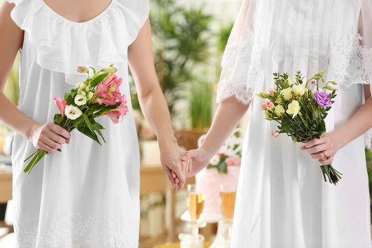 Happy brides holding bouquets of beautiful flowers on lesbian wedding