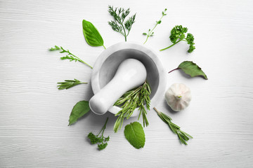 Composition with fresh herbs and mortar on wooden background