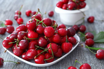 Plate with fresh ripe cherries on table