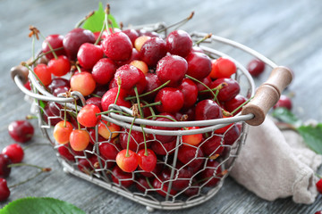 Metal basket with fresh ripe cherries on table