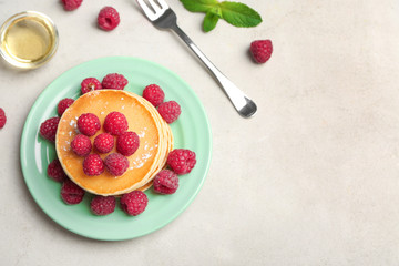 Plate with delicious pancakes on light background