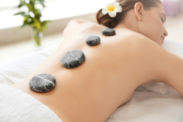 Obraz na płótnie Canvas Young beautiful woman having stone massage in spa salon