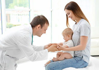 Young mom holding her cute baby while doctor working