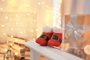 Cute booties for baby on table against blurred Christmas lights