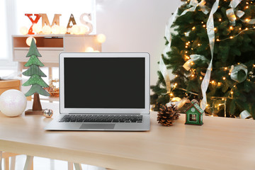 Modern laptop on table and beautiful Christmas decor on background