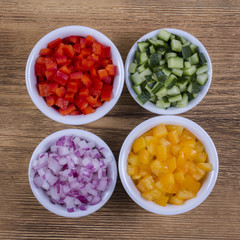 Assortment of vegetables sliced. Peppers, tomatoes, cucumber and onion in bowls
