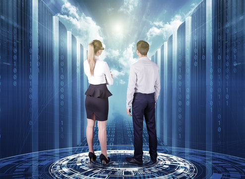 business man and business woman stand on a futuristic hologram and look at the concept of cloud technology among servers in a data center