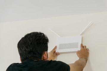 The technicians are installing a wireless internet access point connection on the wall of the room.