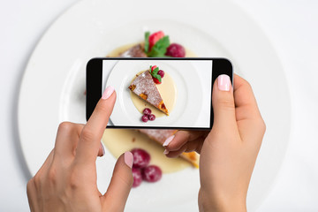 Shooting food on phone's camera. Raspberry Cheesecake on a plate. Food Photographer
