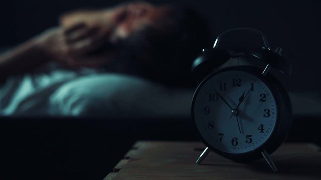 Man talking on mobile phone in bed late at night while getting ready to sleep