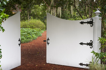 Secret garden entrance gate trail path covered with lush green leaves plants foliage private park oasis