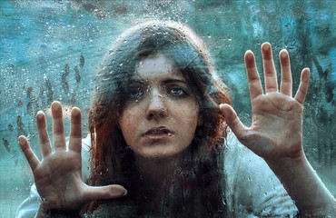 Frightened girl locked in the woods all alone asks for help leaning his hands on the wet scratched...