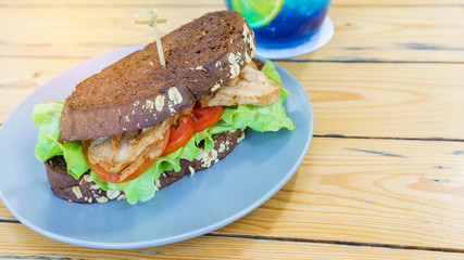 Delicious homemade breast chicken sandwich on blue plate served on wood table