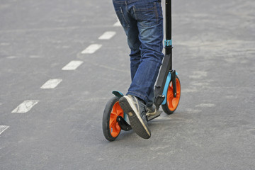 Obraz premium The legs of a child riding a scooter.