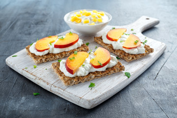 Homemade Crispbread toast with Cottage Cheese and nectarine on white wooden board.
