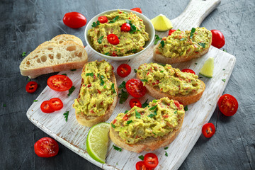 Homemade Guacamole toast with chili pepper, parsley on white wooden board