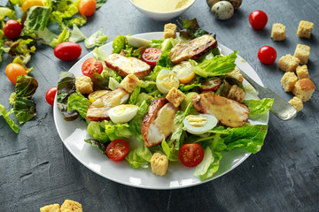 Fresh healthy Caesar salad with chicken, egg quail, tomatoes, Cheese and Croutons in a white plate