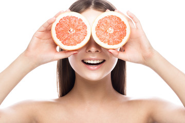 Beautiful young girl with a light natural make-up and perfect skin with Grapefruit in her hand. Beauty face. Picture taken in the studio on a white background.