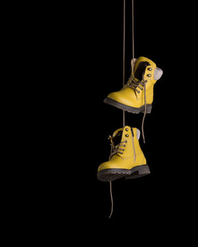 Timberland boots yellow on a black background. Boots hanging on laces. 스톡  사진 | Adobe Stock